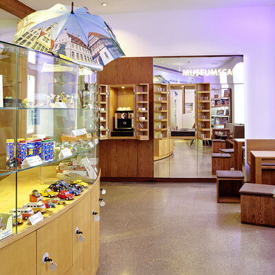 Bild vergrößern: Museumsshop mit Produkten und Sitzgelegenheiten für Besucher