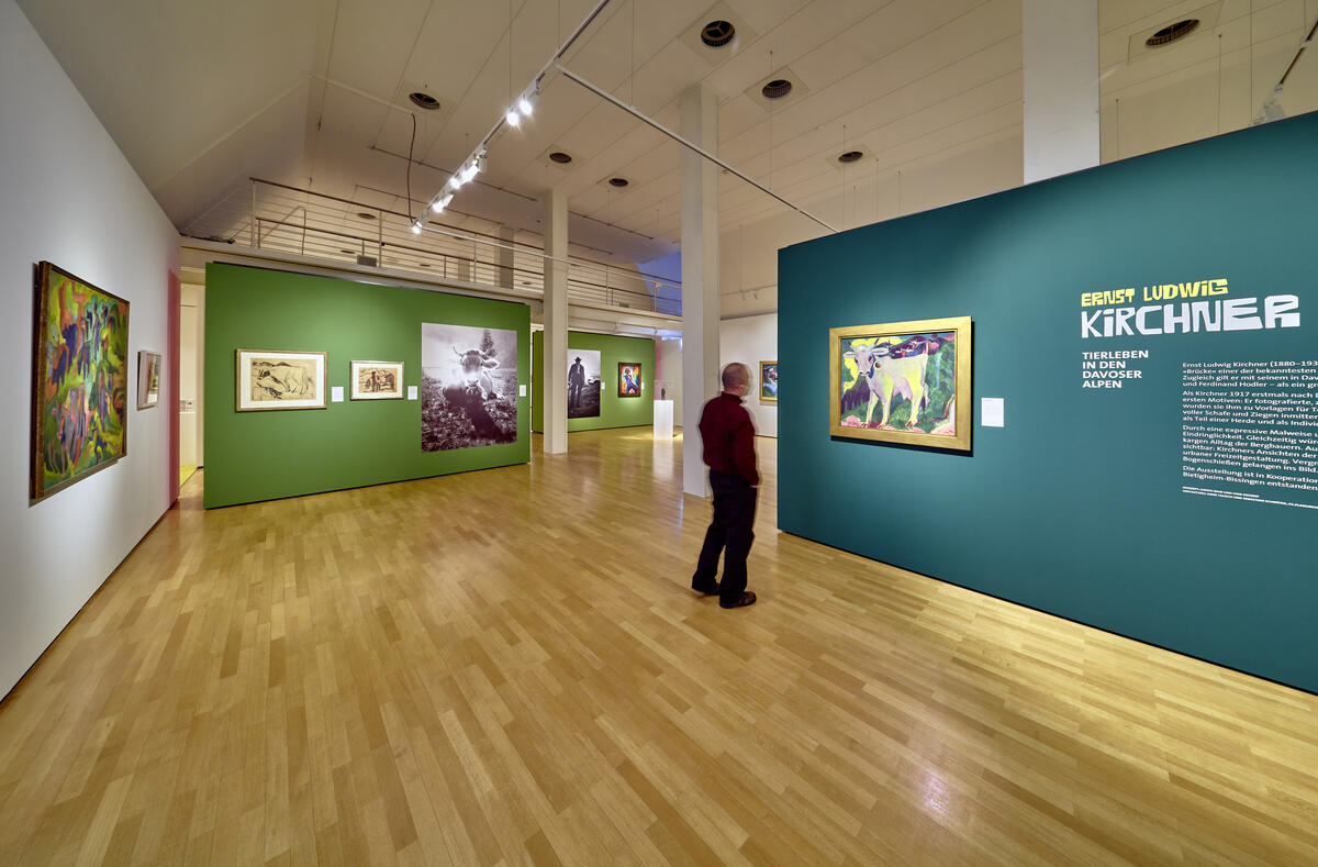 Bild vergrößern: Ausstellungsraum mit Werken an grünen Wänden und einer Person, die das Gemälde einer weißen Kuh betrachtet.