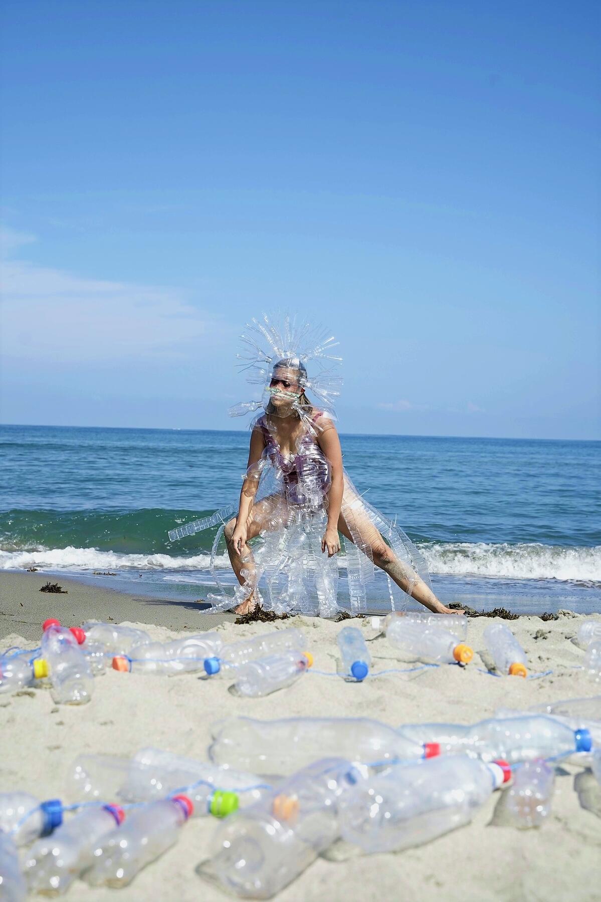 Bild vergrößern: Screenshot aus dem Video "Bari-bari" von Ea Torrado and Chino Neri mit einer Tänzerin am Strand, deren Kostüm aus weggeworfenen Plastikflaschen besteht.